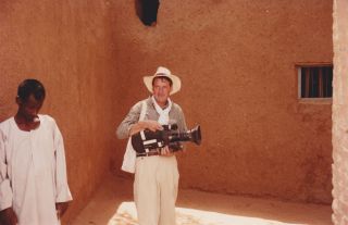 Younger Michael Palin with a film camera on his travels