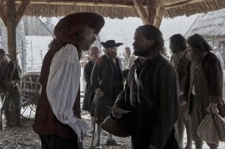 Trepagny (David Thewlis) speaks to his servant Rene Sel (Christian Cooke) in the Trade Hall in Wobik
