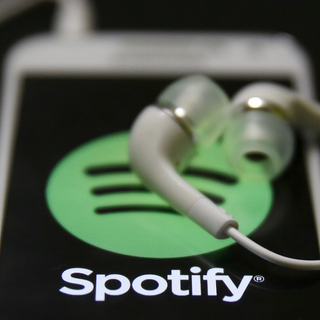 Earbuds restiing on phone display, above the Spotify logo