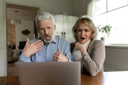 A couple looks at a computer screen with a shocked expression