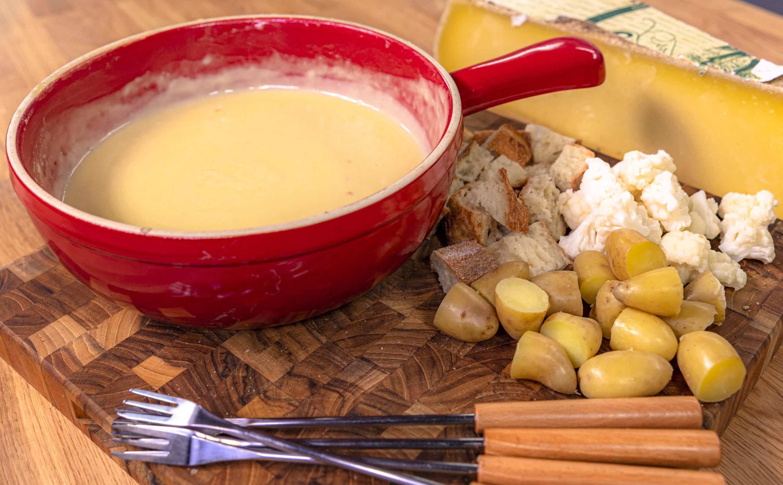 A dish of Raymond's cheese fondue with bread and vegetables to dip