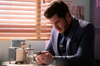 Gray looks at his car's journey tracker in EastEnders